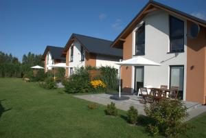 a house with umbrellas in a yard with a grass yard at Domki Kalinowa14 Kopalino in Kopalino