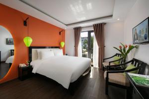a bedroom with a white bed and an orange wall at Hoi An Golden Holiday Villa in Hoi An