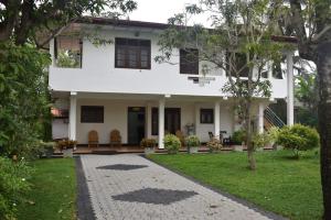 a white house with a pathway in front of it at Happy Garden in Dodanduwa