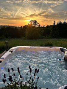 - un bain à remous dans un champ avec le coucher du soleil en arrière-plan dans l'établissement Mosel Urlaub Stabenhof - Whirlpool, Natur und Grill, à Brodenbach