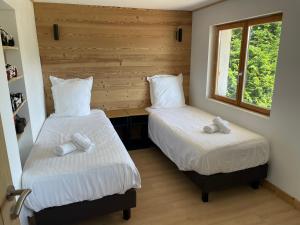 two beds in a room with two windows at Chalet les brimbelles in Le Tholy