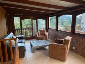 a living room with chairs and a table and windows at Chalet les brimbelles in Le Tholy
