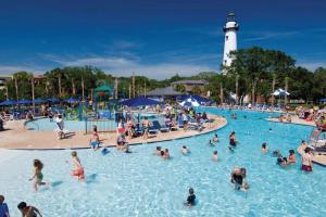 a group of people in a swimming pool with a lighthouse at Pierside Retreat Saint Simons Island 3BR Sleeps 8 in Saint Simons