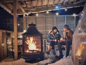 deux personnes assises sur un banc à côté d'une cheminée dans l'établissement Necoana Glamping Annovillasグランピング, à Fujikawaguchiko 52 autres photos