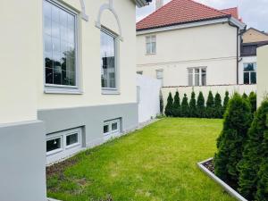 a backyard of a white house with a green lawn at Villa i Fridhem centralt i Malmö in Malmö