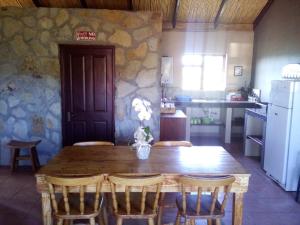 a kitchen with a wooden table and chairs and a kitchen with a refrigerator at Kampala Farm in Bonnievale