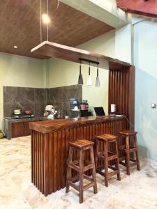 a kitchen with a bar with three wooden stools at Villa Sibolangit Satu Hati near Hillpark with private pool in Bandarbaru