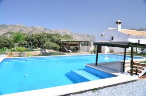 a swimming pool with a house and mountains in the background at Cortijo Los Santeros in Castril