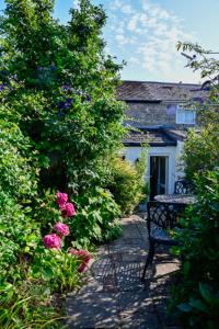 a bench sitting in front of a house with flowers at Cosy cottage in Bridport centre in Bridport