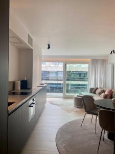 a kitchen and living room with a couch and a table at Orfeo Knokke in Knokke-Heist