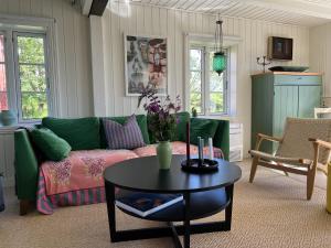 a living room with a green couch and a table at Historic House, 1880 - Stunning Panoramic Views in Sørvågen