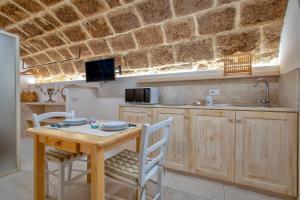 eine Küche mit einem Holztisch, Stühlen und einer Theke in der Unterkunft Deliloft in Alghero + 14 Fotos