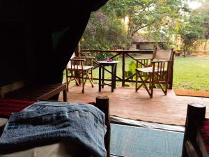 a wooden deck with chairs and a table and a table at Simbamwenni Lodge and Camping in Morogoro