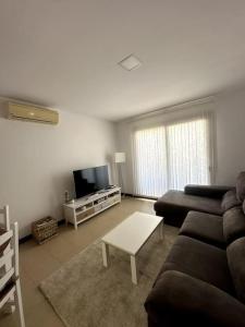 ein Wohnzimmer mit Sofa und Fernseher in der Unterkunft Residencial Noray Duplex 26 in Puerto Calero