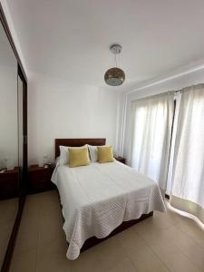 a white bedroom with a bed with two yellow pillows at Residencial Noray Duplex 26 in Puerto Calero +25 photos