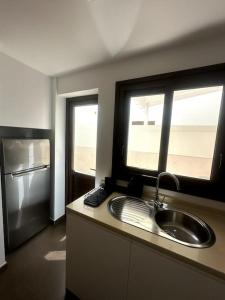 eine Küche mit Spüle und zwei Fenstern in der Unterkunft Residencial Noray Duplex 26 in Puerto Calero