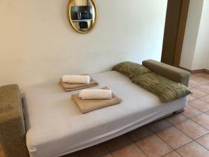 a couch with two pillows and a mirror on the wall at Vacanza a Miglieglia in Miglieglia