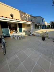 a patio with white tables and chairs on a building at Les aigrettes in Saint-Pierre-dʼOléron