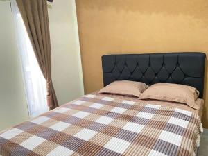 a bedroom with a bed with a checkered blanket at Djogja Homestay Syariah in Piyungan