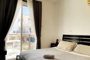 a bedroom with a bed and a large window at Apartments with a luxurious location near the sea in Paphos