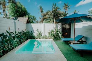 a backyard with a pool and an umbrella and benches at Villa on Air in Gili Islands