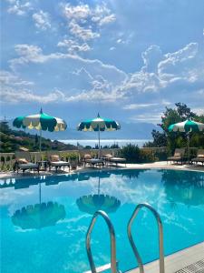 a swimming pool with chairs and umbrellas at Monte Aria panorama suites in Herceg-Novi