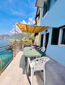 un tavolo verde e sedie su un balcone con vista sull'oceano di affittacamere nuova Vandiris a Manarola