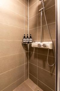 a bathroom with a shower with four bottles on a shelf at High floor view accommodation in Busan