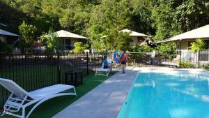 a swimming pool with two chairs and a person sitting in a chair next to it at King Safari Tent 3 in Nelly Bay +2 photos