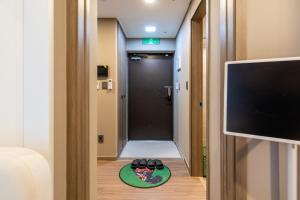 a room with a hallway with a television and shoes on the floor at High floor view accommodation in Busan