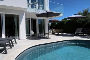 a swimming pool with chairs and umbrellas next to a house at Art Villa Malija in Portorož