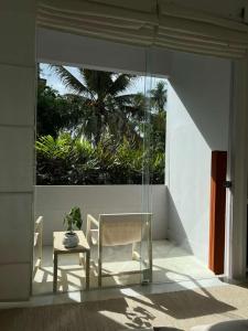 a glass room with a table and a chair at Saffron Robes Living in Hikkaduwa