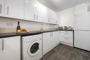 a white kitchen with a washing machine and a bottle of wine at 4BR 3 bath Spacious apartment, Sleeps upto 8 free parking in Allesley