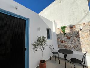 a patio with a table and chairs next to a stone wall at Casa Stergia - Village Project in Psinthos