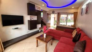 a living room with a red couch and a tv at Heritage Exotica Villa 3BHK JAQK Holidays in Arpora