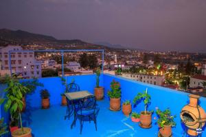 a blue balcony with a table and chairs and potted plants at Casa Voyager 'secret garden terrace' in Chefchaouen