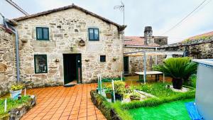 a stone house with a courtyard in front of it at Casa a Voada - Rural con Piscina Privada, Barbacoa y Juegos in Muiños
