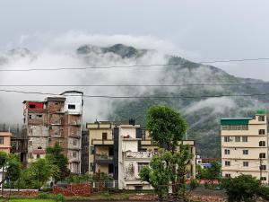a group of buildings in front of a mountain at Welcome Home Stay & Hotel Tapovan Rishikesh in Rishīkesh