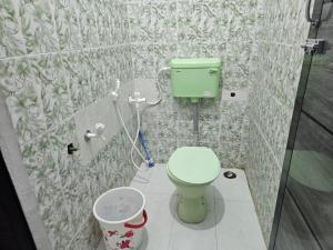 a bathroom with a green toilet in a shower at SHIs Spandha Apartments Near Coimbatore Airport in Coimbatore +37 photos