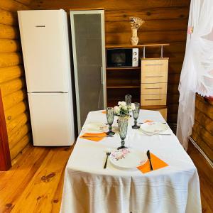 a table with a white table cloth and a refrigerator at Еко котедж Яблуницька троянда in Yablunytsya