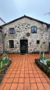 a stone building with a door and a brick patio at Casa a Voada - Rural con Piscina Privada, Barbacoa y Juegos in Muiños