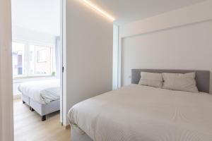 een witte slaapkamer met een bed en een spiegel bij Maison Anna by Exclusive-Stays in Oostende