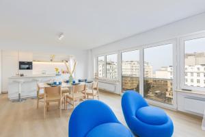 een woonkamer met blauwe stoelen en een tafel en een keuken bij Maison Anna by Exclusive-Stays in Oostende