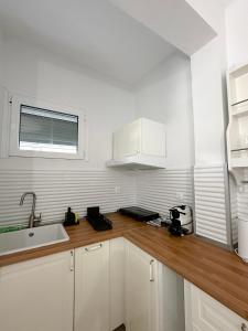 a kitchen with white cabinets and a sink and a window at Petra Mare Apartments in Alyki