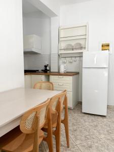 a kitchen with a white refrigerator and a table and chairs at Petra Mare Apartments in Alyki