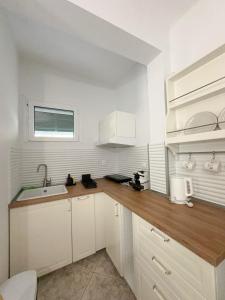 a kitchen with white cabinets and a wooden counter top at Petra Mare Apartments in Alyki