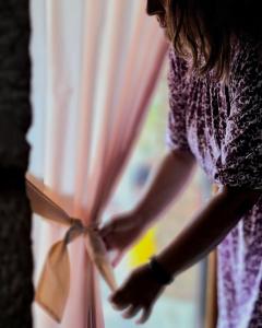 a woman opening a window with a pink curtain at la terrazza sul viale in Circello