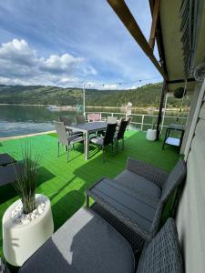 a patio with a table and chairs on the water at Casa pe lac Bicaz in Bicaz +28 photos