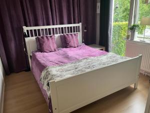 un letto bianco con lenzuola e cuscini viola; di Mysigt rum i trevligt hus a Taberg