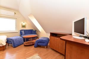 a room with blue chairs and a tv on a desk at Vilaverona in Palanga